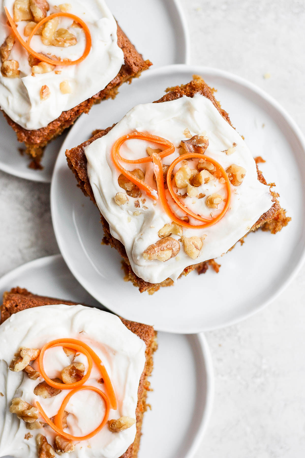 Three slices of gluten free carrot cake on plates.