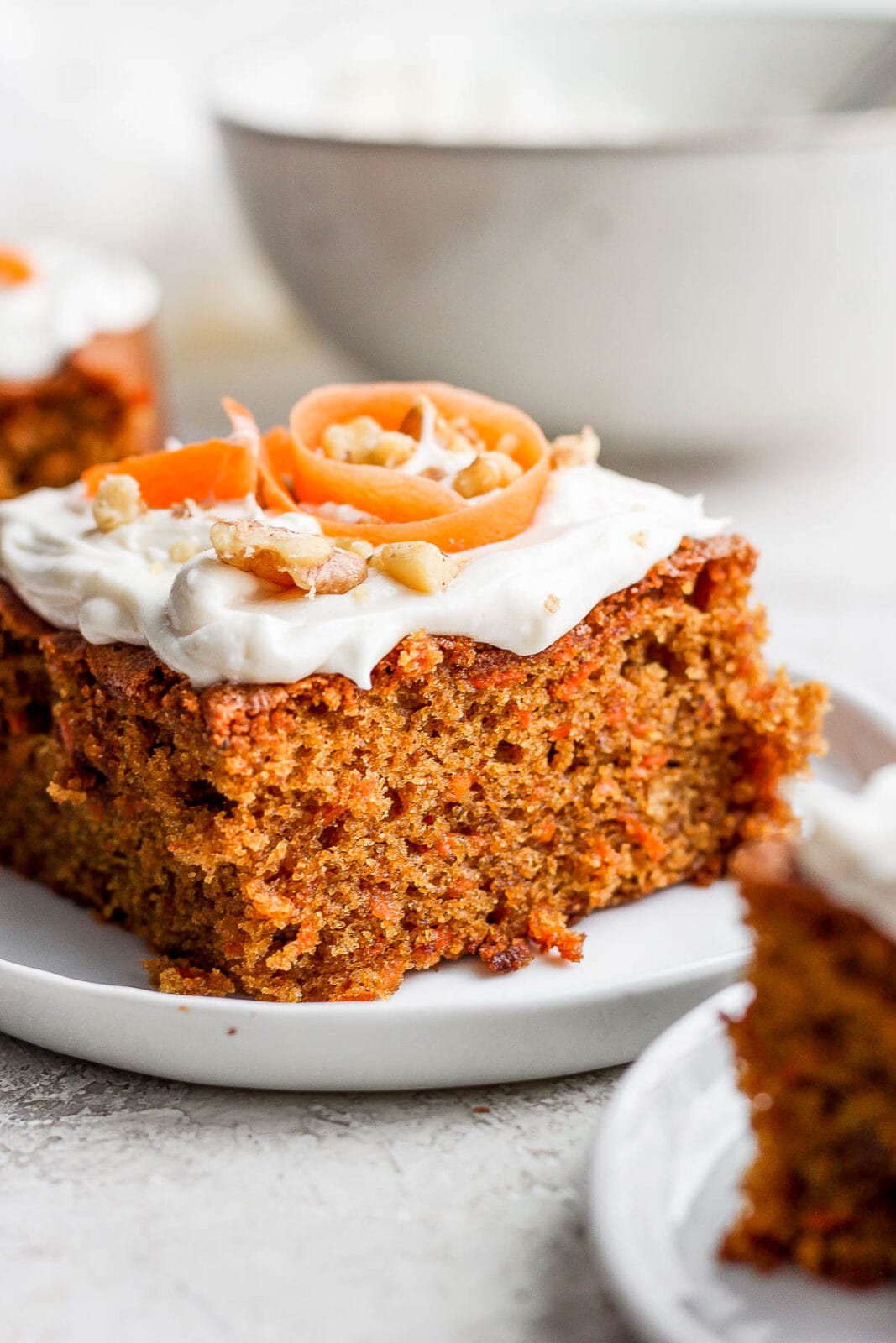 Plate with a slice of carrot cake topped with dairy free cream cheese frosting.