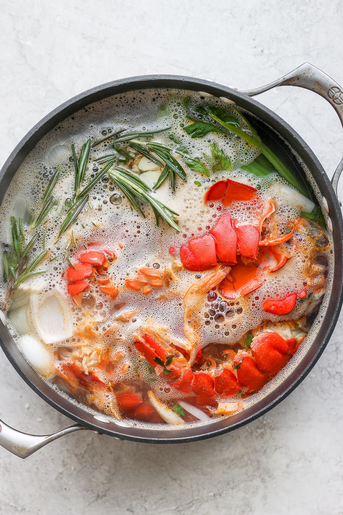 Dutch oven with seafood stock ingredients after being boiled.