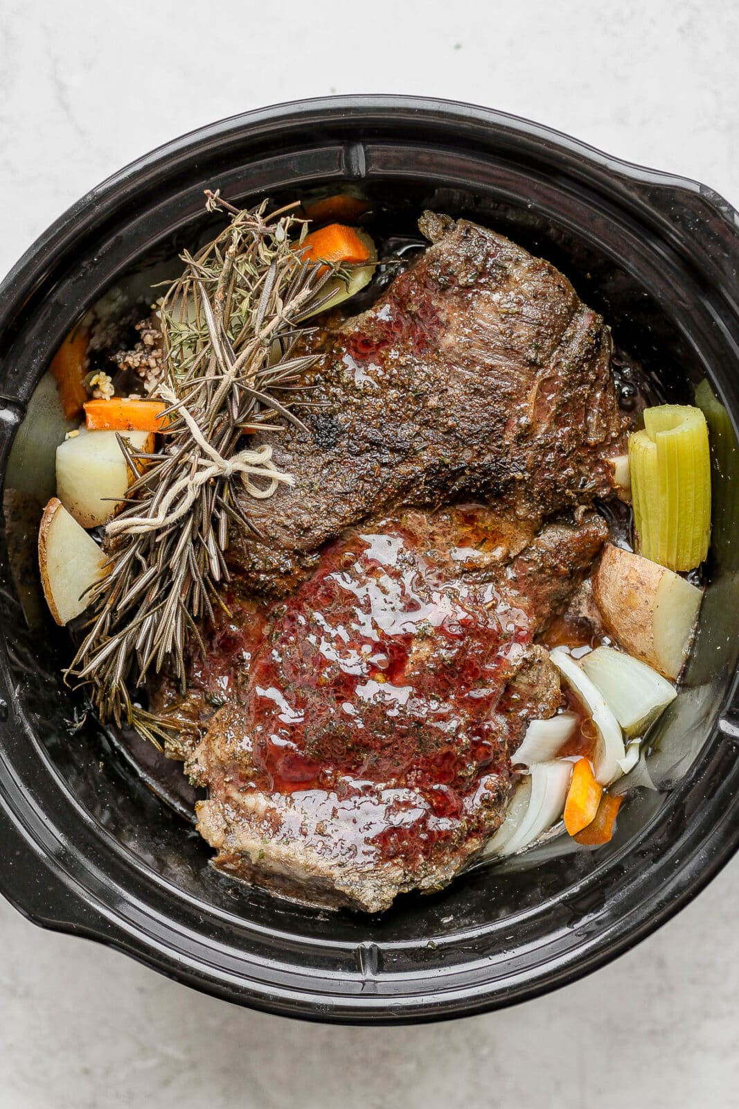 Slow cooker with beef pot roast after cooking.