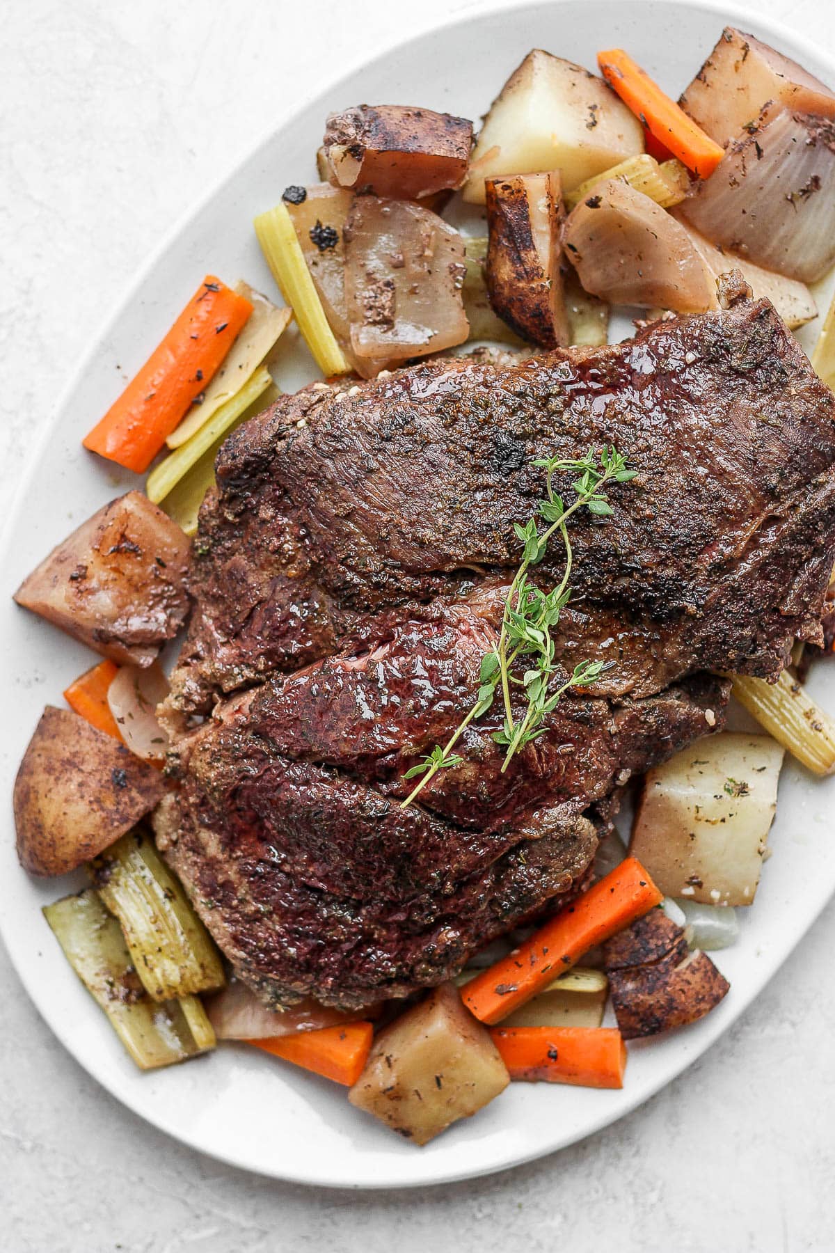 Large white plate with cooked slow cooker pot roast and vegetables.