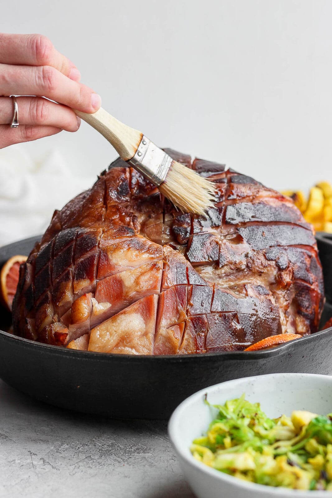 Smoked ham being basted in a cast iron skillet.