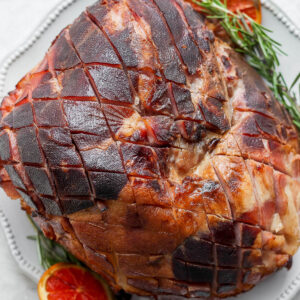 A ham that has been scored sitting on a large platter.