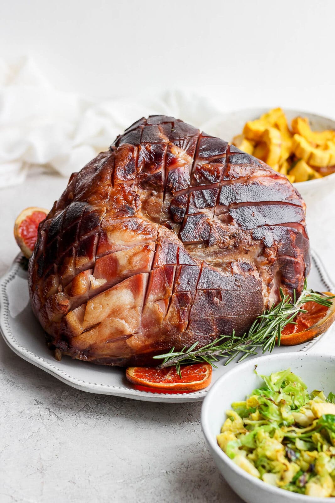 Ham on a plate with rosemary and orange slices.