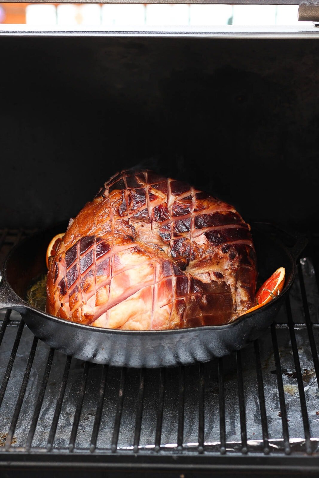 Ham in a cast iron pan in a smoker.