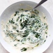 A white bowl with vegan ricotta fully mixed with a spoon.