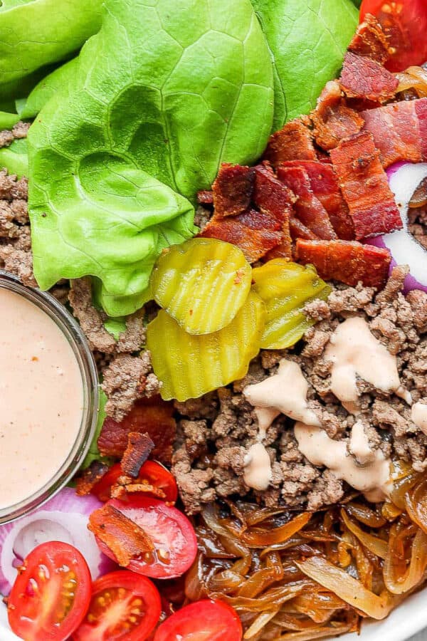 A Burger Bowl filled with burger sauce, lettuce, pickles, bacon, tomatoes and caramelized onions.