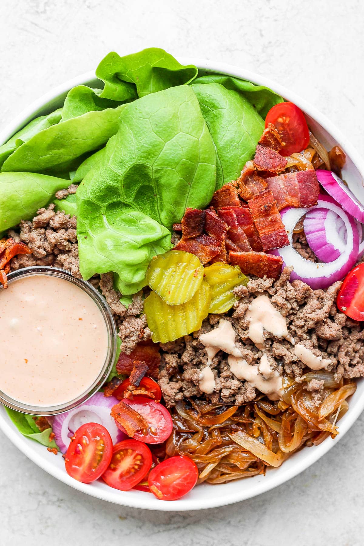 Fully assembled burger bowl in a bowl plus a small dish of burger sauce.