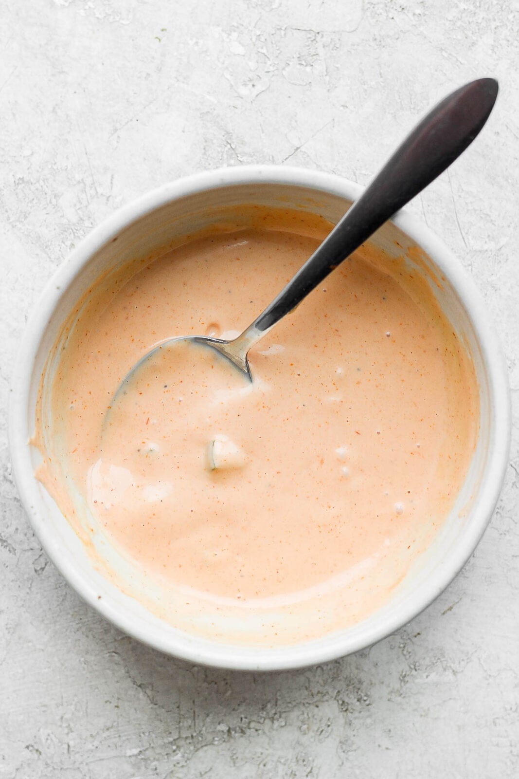 Burger sauce ingredients mixed with a spoon in a bowl.