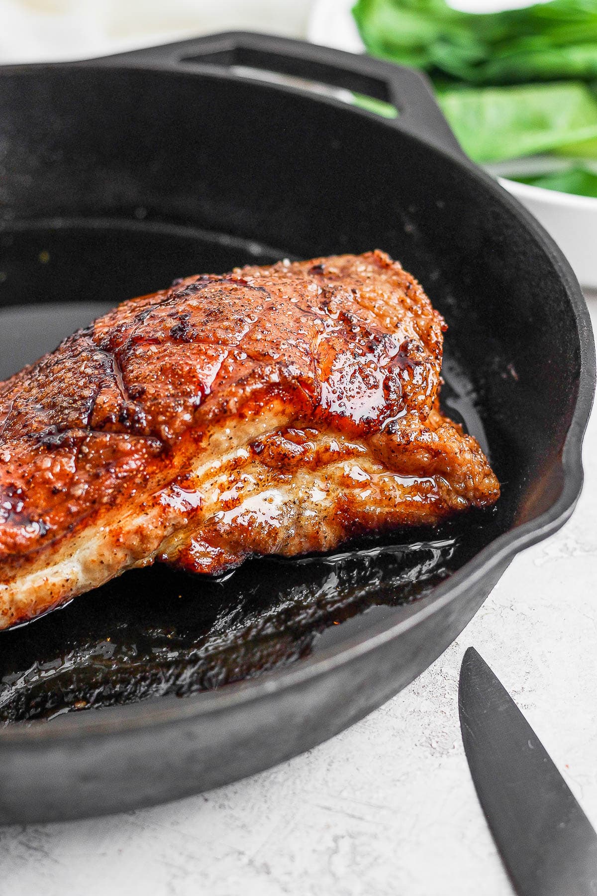 A roasted slab of pork belly in a cast iron skillet. 