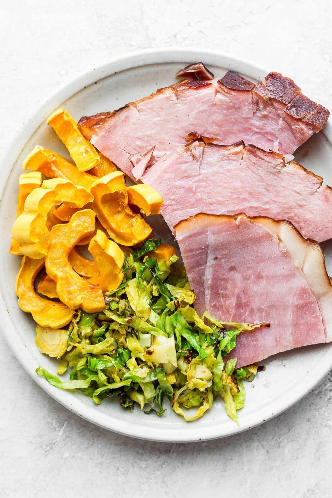 Plate of smoked ham, shaved brussel sprouts and delicata squash.