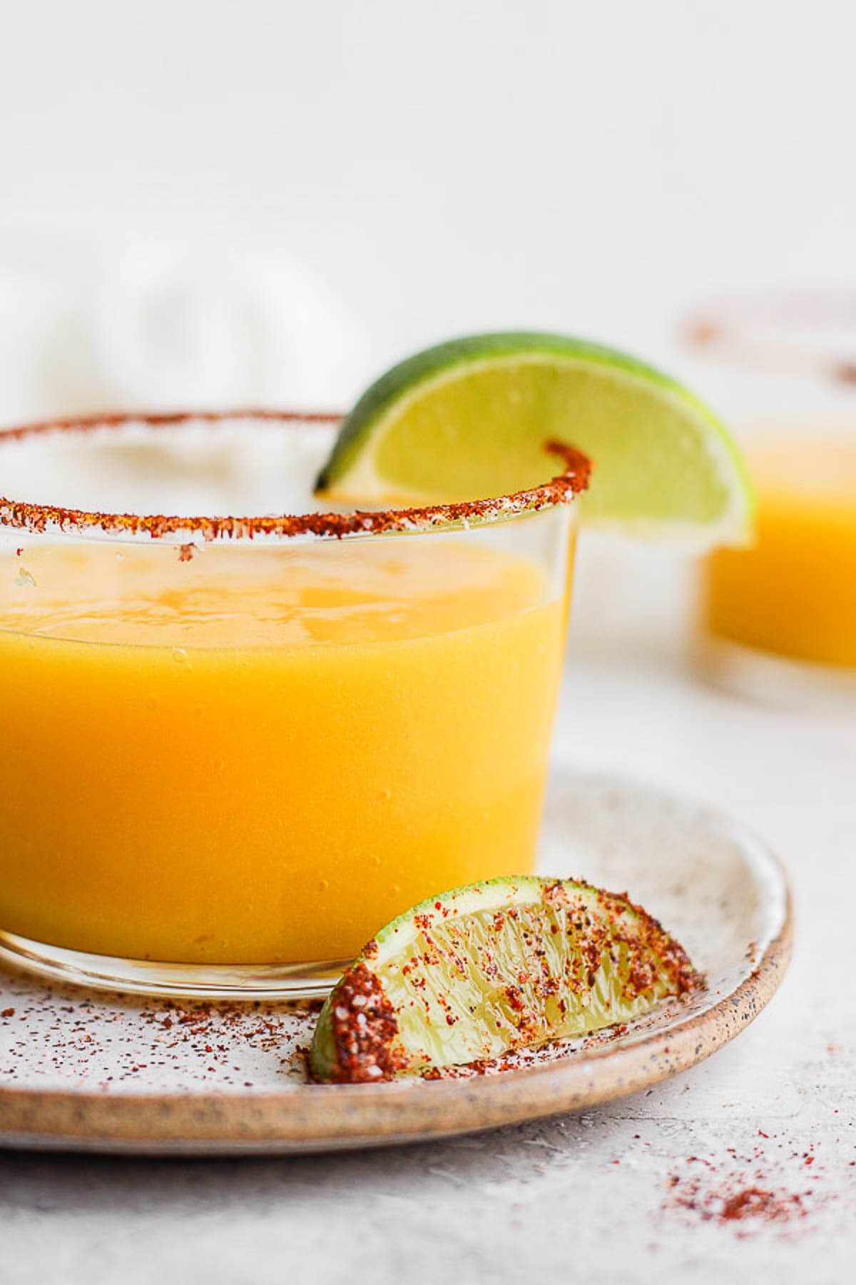 Mango Margarita in a glass with a chili lime rim and fresh lime. 