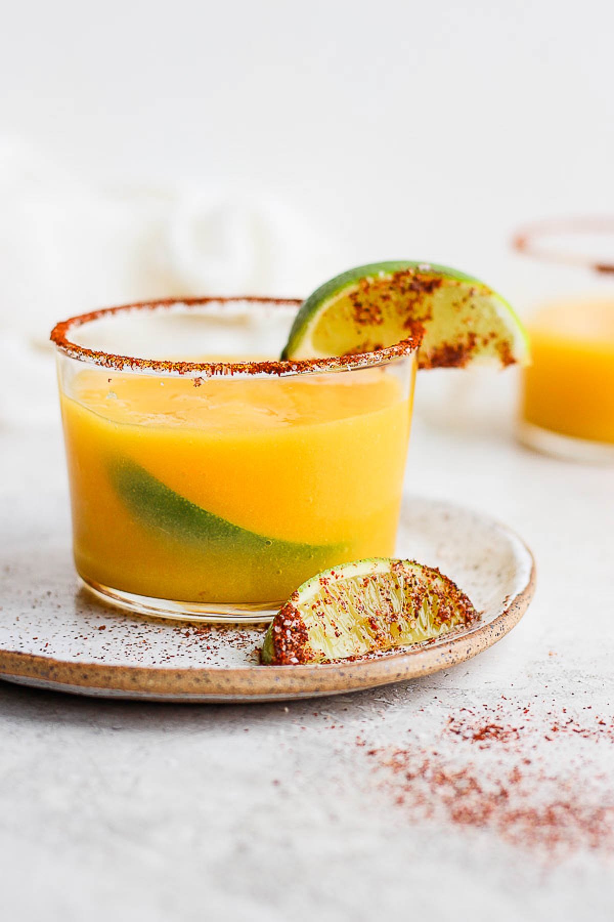 Mango Margarita in a glass with a chili lime rim and fresh lime. 