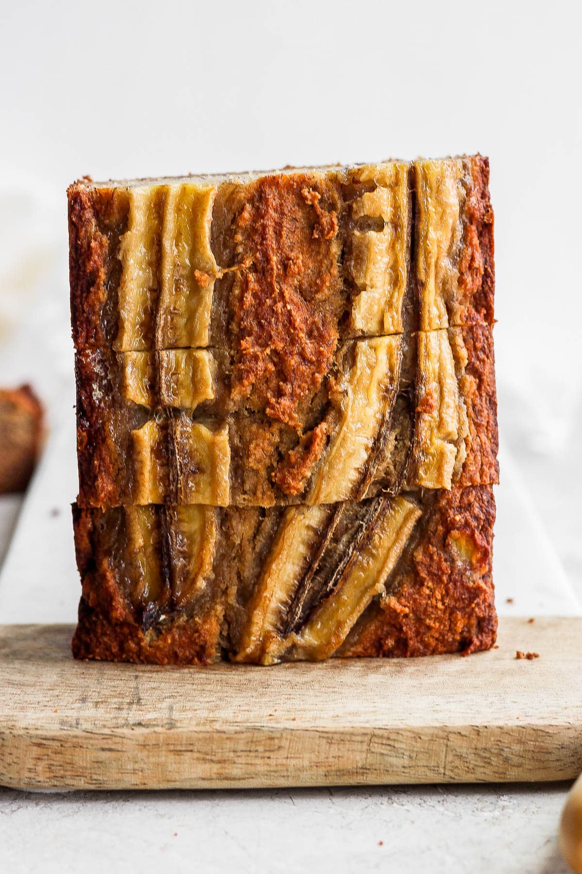 Slices of paleo banana bread stacked on a cutting board.