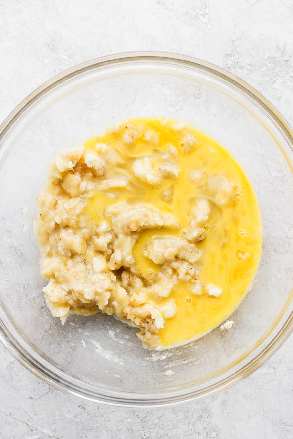 A bowl of mashed bananas and a beaten egg.