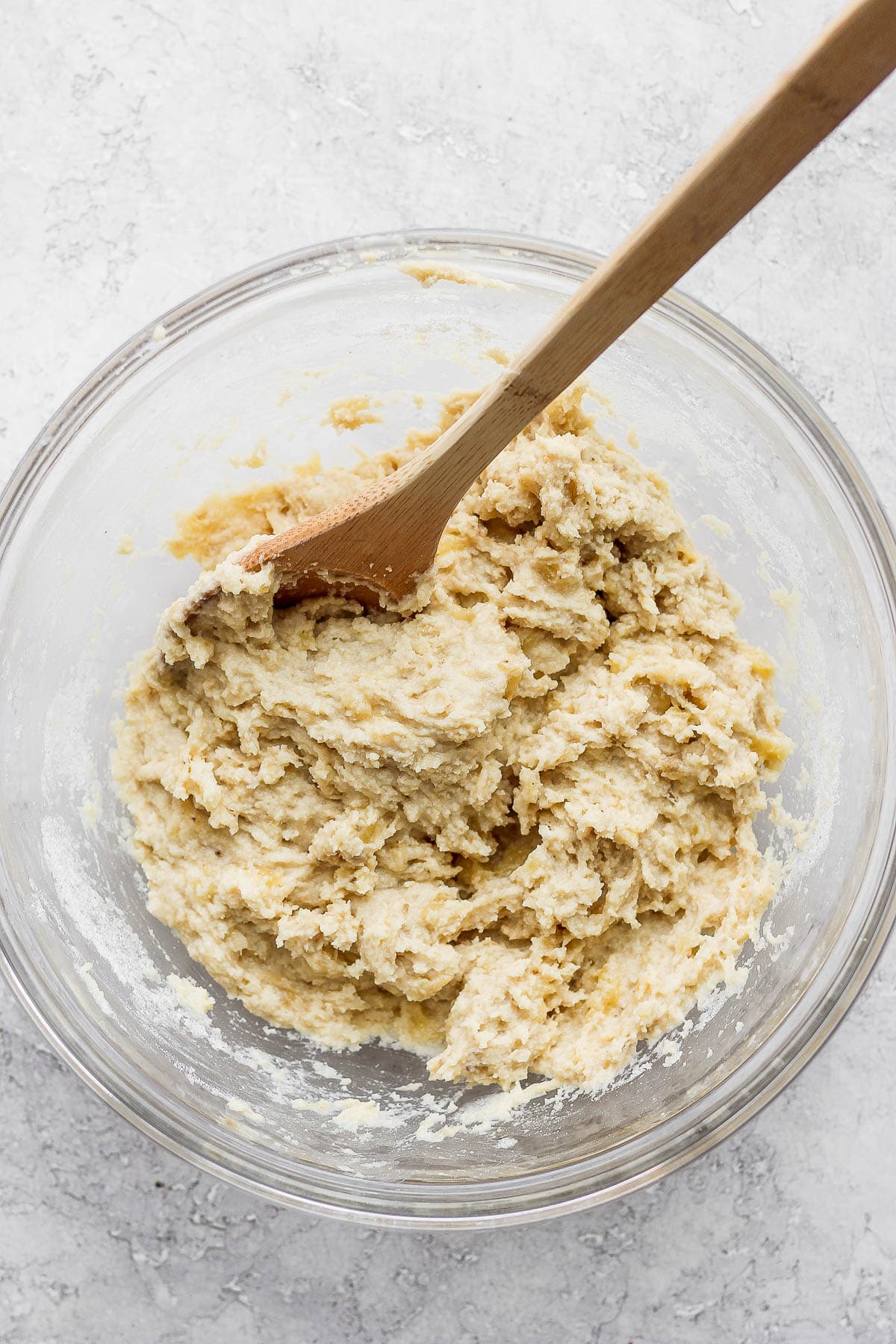 A bowl of paleo banana bread batter with a wooden spoon.