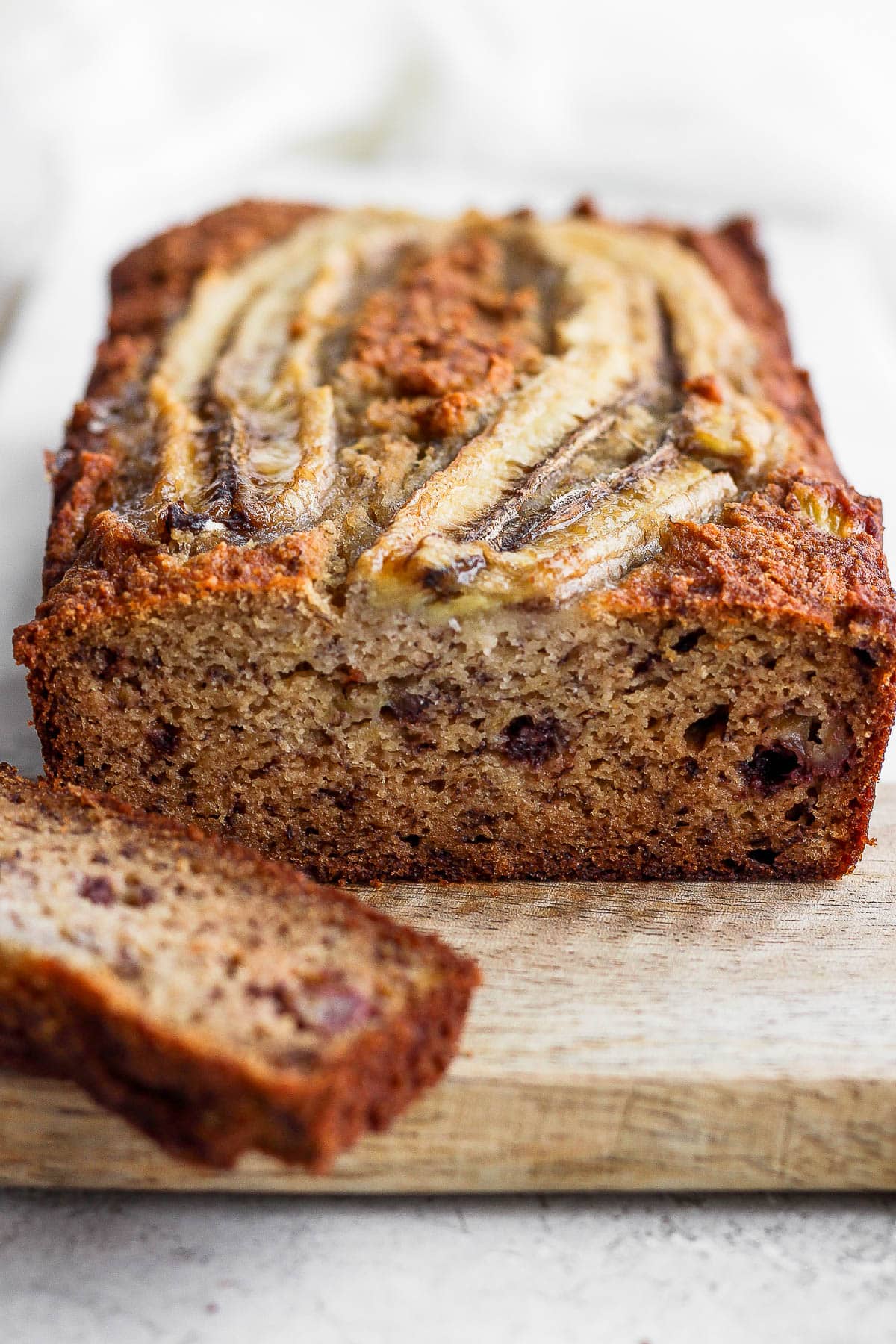 Paleo banana bread on a cutting board after a piece was sliced off.