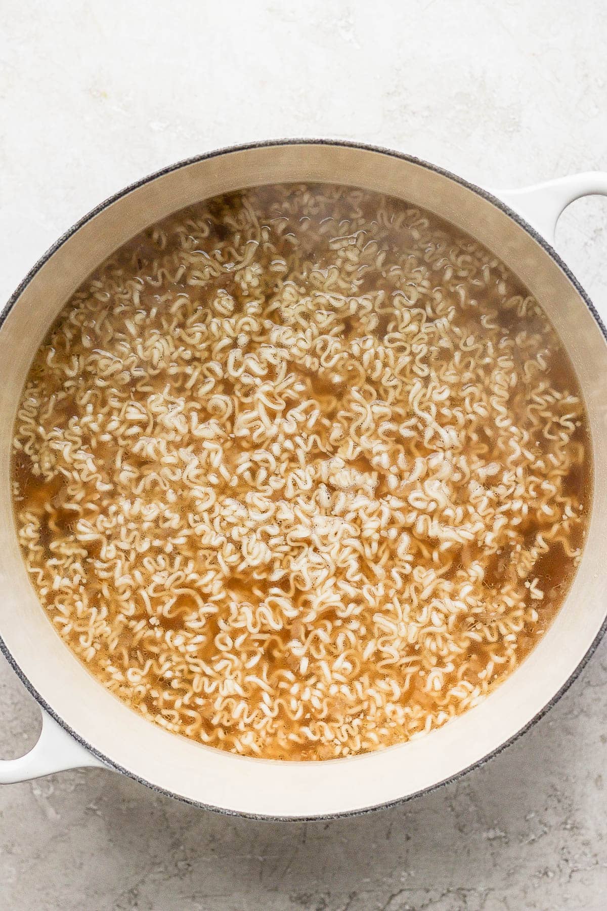 Ramen noodles now added to the dutch oven with broth for pork belly ramen.