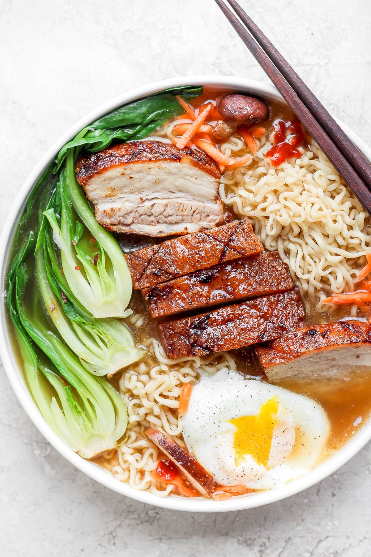 Pork belly ramen in a bowl with a poached egg and chopsticks.