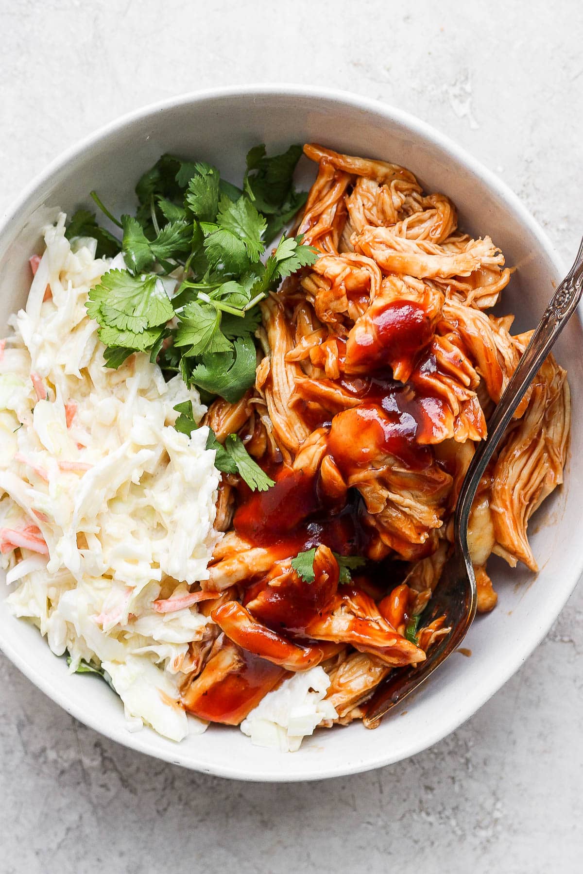 A bowl of creamy coleslaw and BBQ chicken.