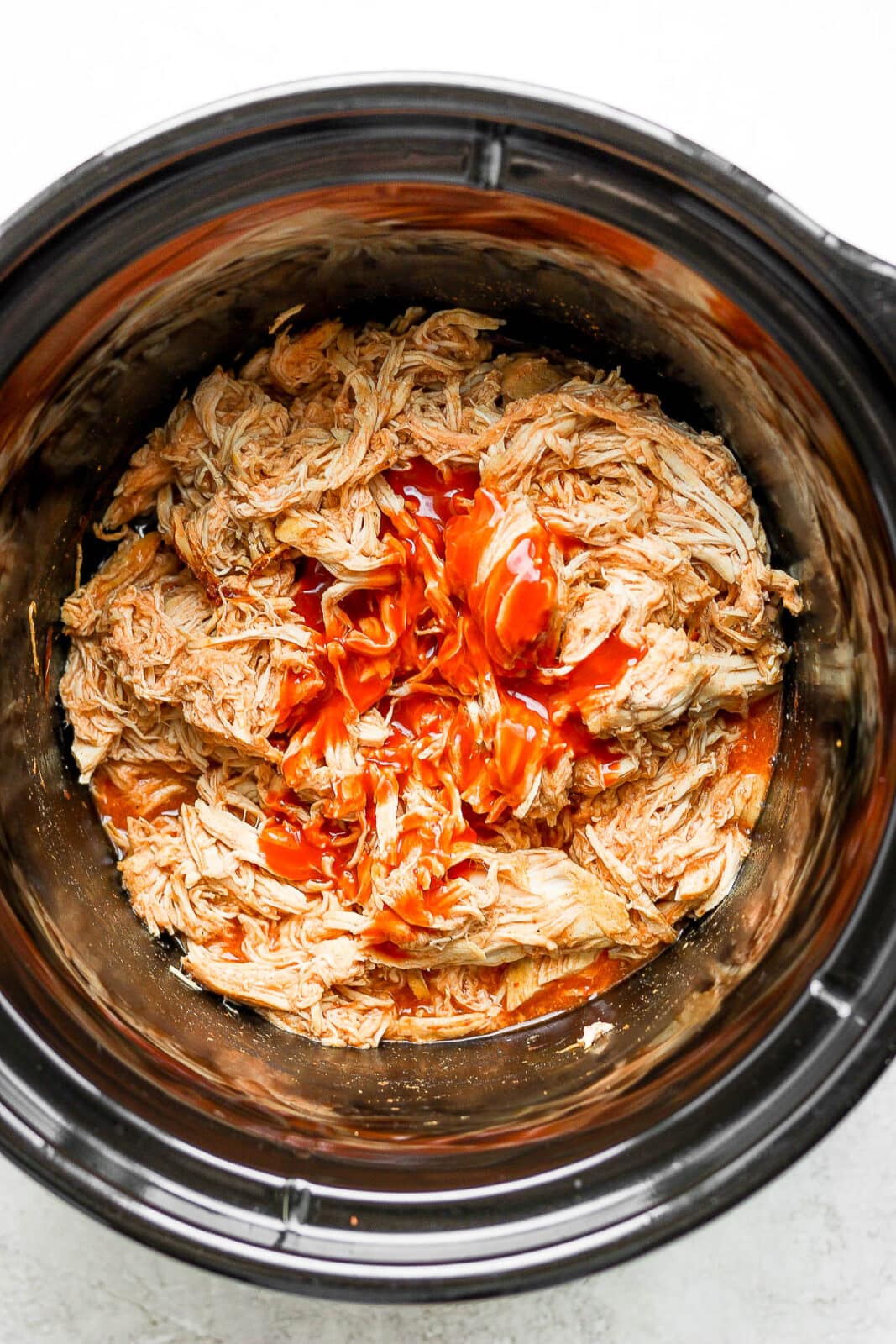 Slow cooker buffalo chicken with the last of the buffalo sauce added.