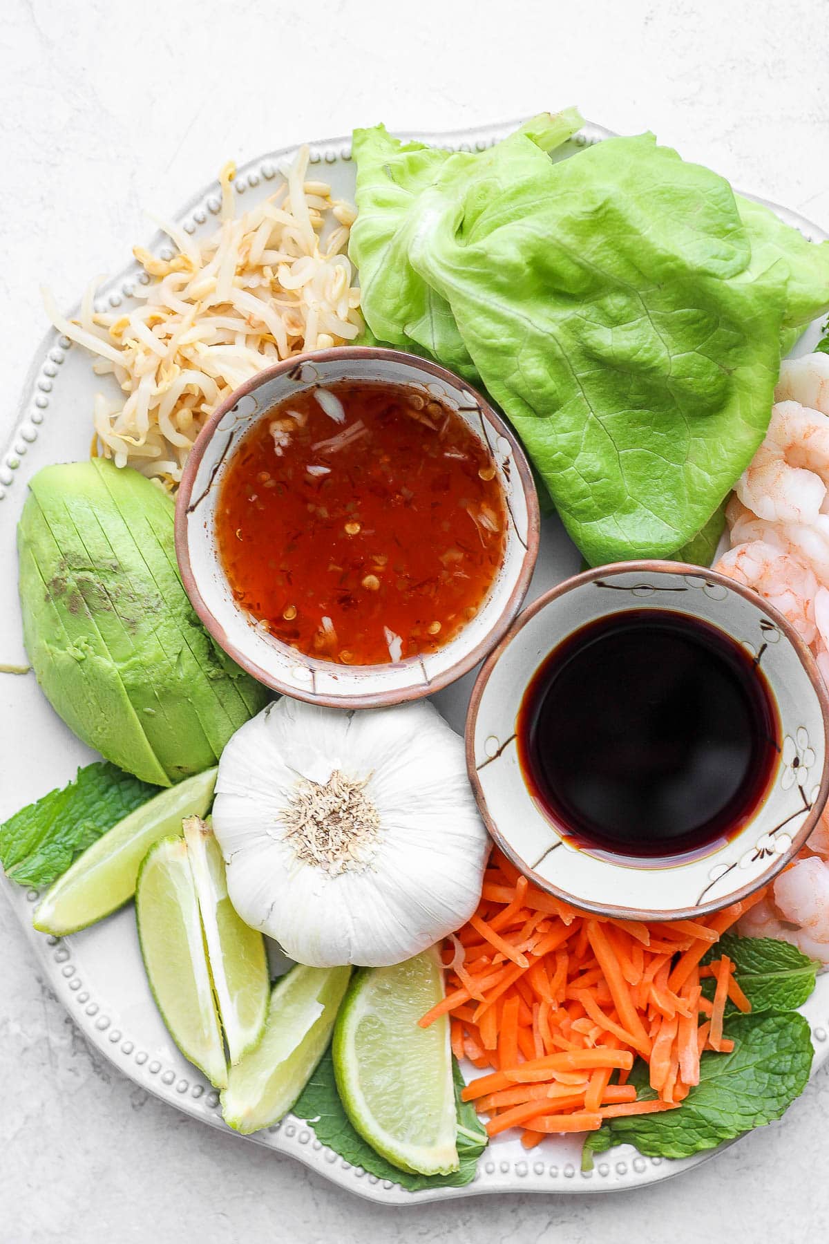 Plate with spring roll ingredients and a dish of spring roll dipping sauce.