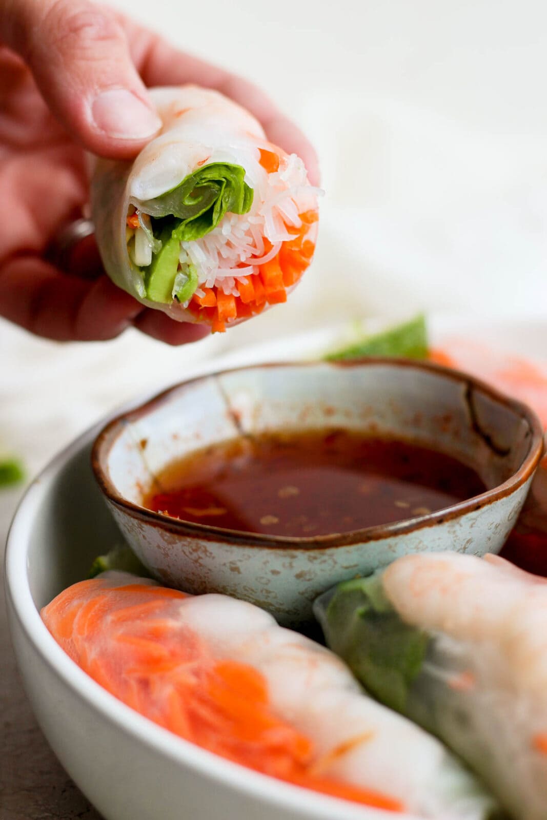 A spring roll being dipped into the dipping sauce.