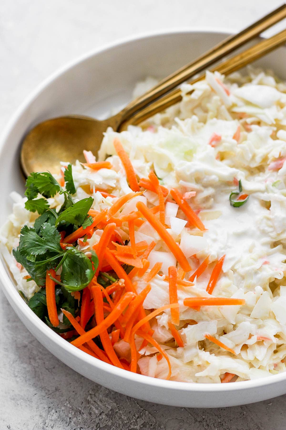 A bowl of creamy coleslaw and 2 spoons.