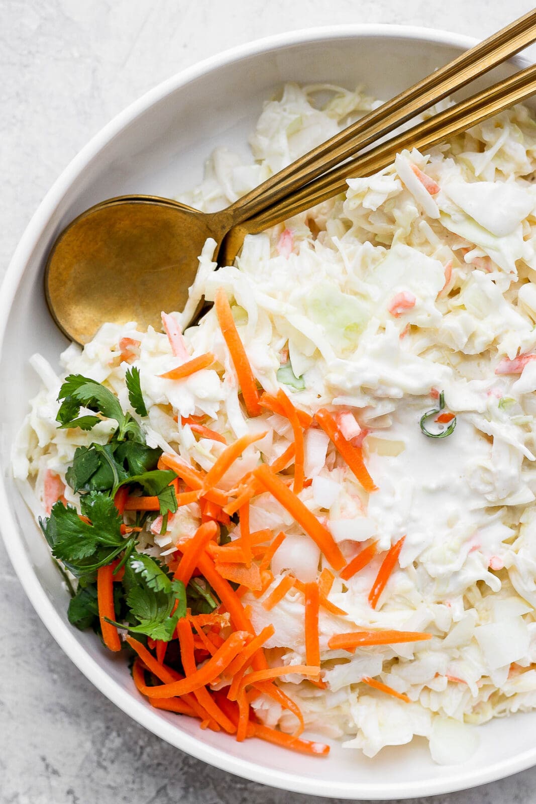 Creamy coleslaw in a bowl with spoons.