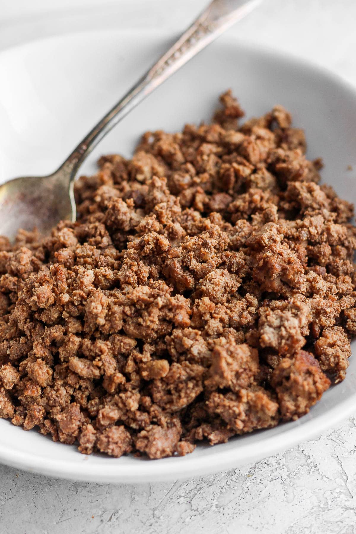 Cooked taco meat in a dish with a spoon.