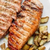 Two grilled pork tenderloins on a plate with potatoes.