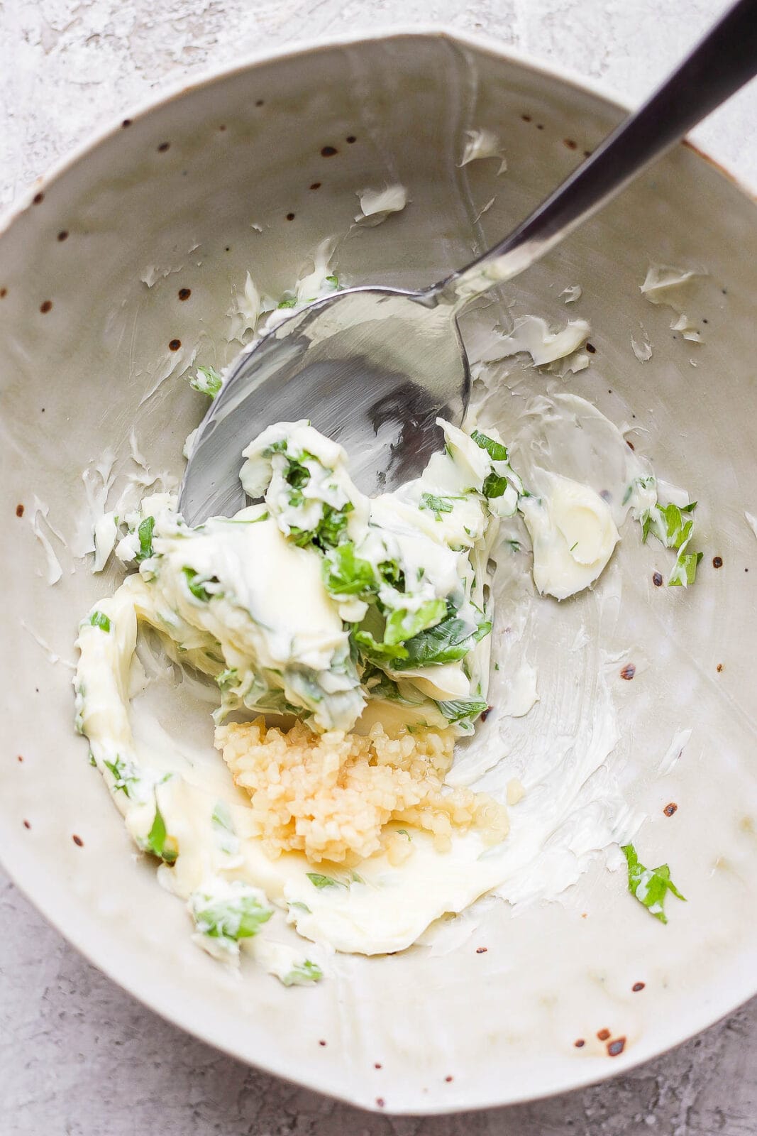 Herbed butter ingredients being mixed in a bowl.