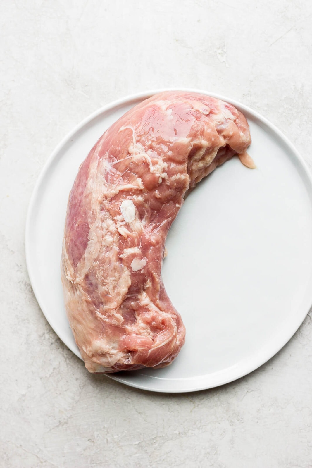 Raw pork tenderloin on a plate. 