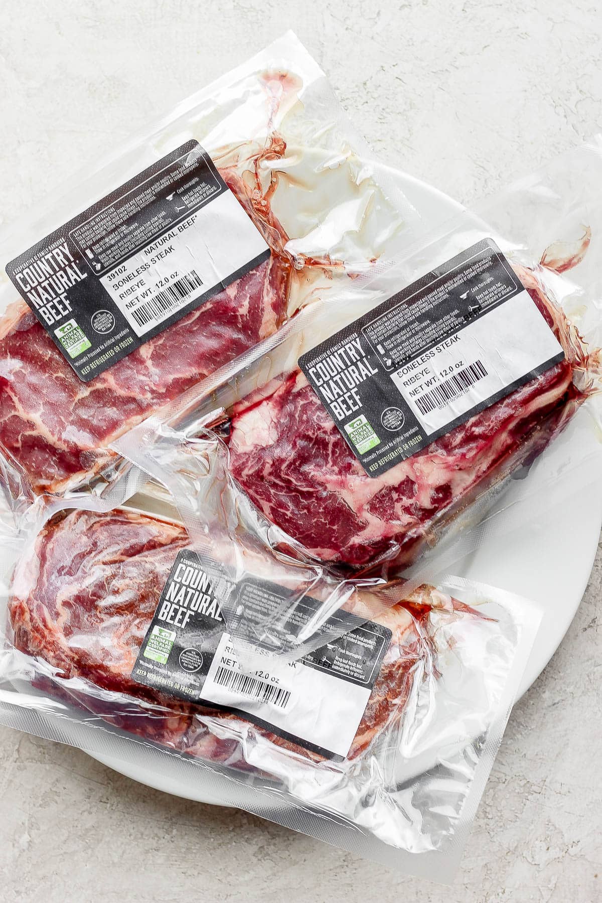Three country natural beef ribeye steaks in packaging. 