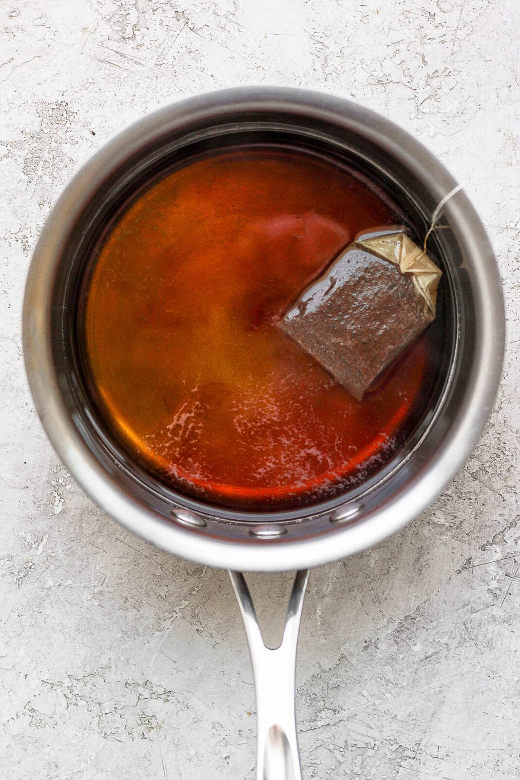 Earl Grey tea being steeped in a saucepan of hot water.