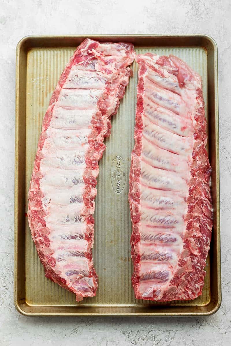 Two racks of ribs on a baking sheet with their membranes removed. 