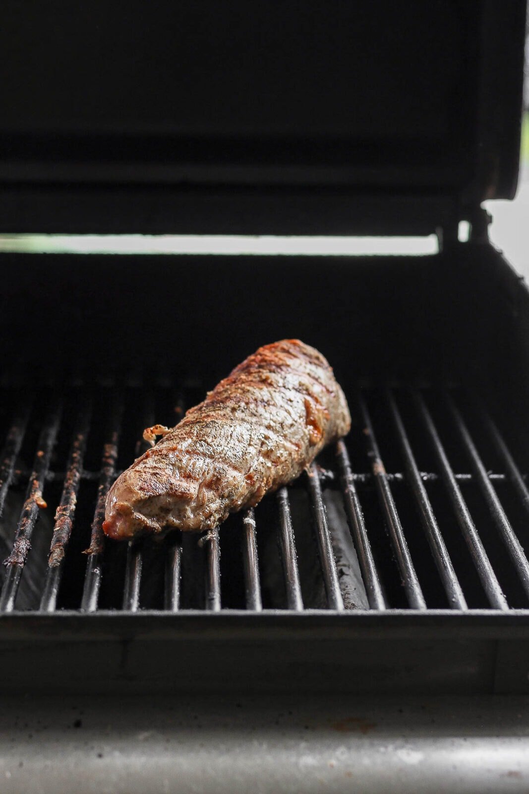 Two pork tenderloins on a smoker.