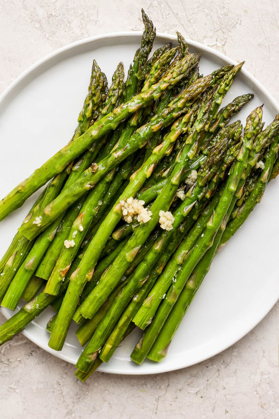 Smoked asparagus on a plate with some added garlic.