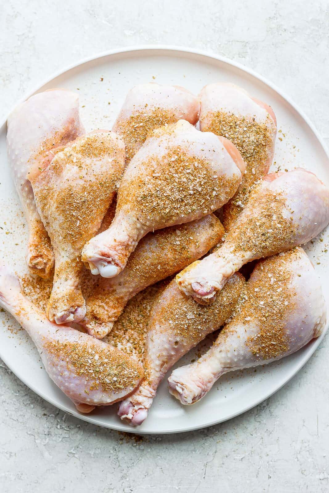 A plate of chicken legs covered in dry rub. 