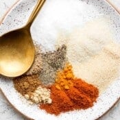 Spices for a smoked chicken dry rub on a small plate with a gold spoon.