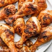 Several smoked chicken legs piled on a large plate.