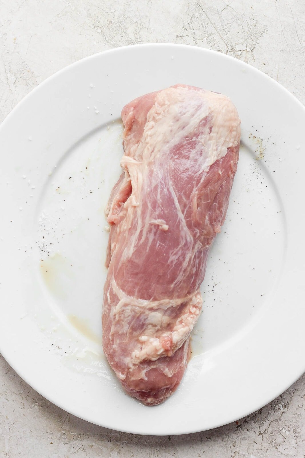A raw pork tenderloin on a plate. 