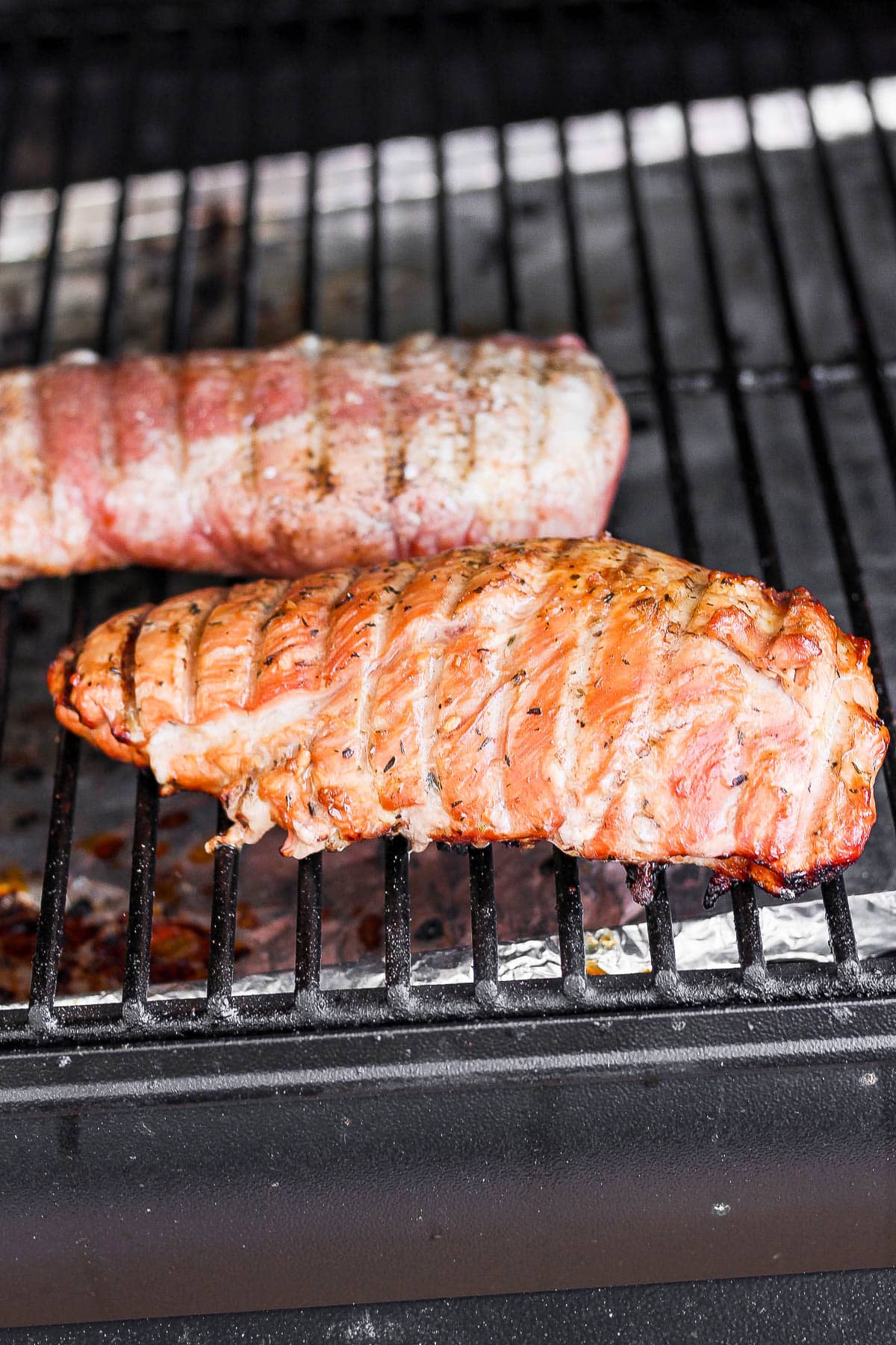 Two pork tenderloins on a smoker. 