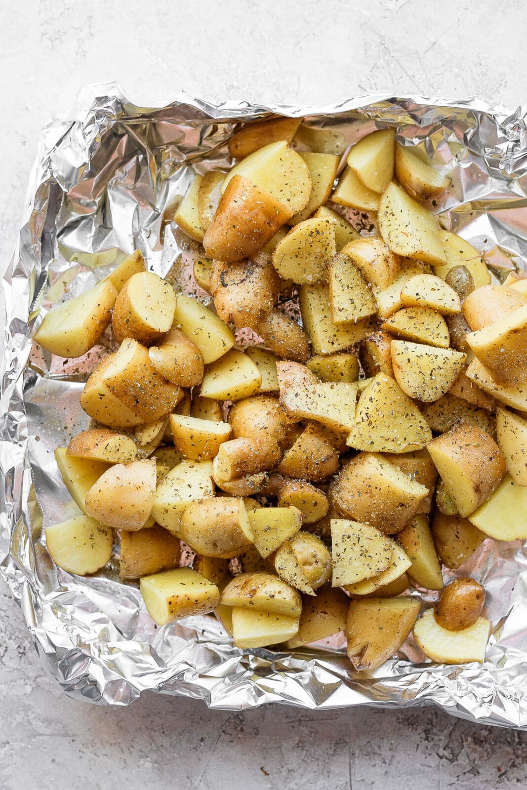 Seasoned potatoes in an aluminum foil boat.