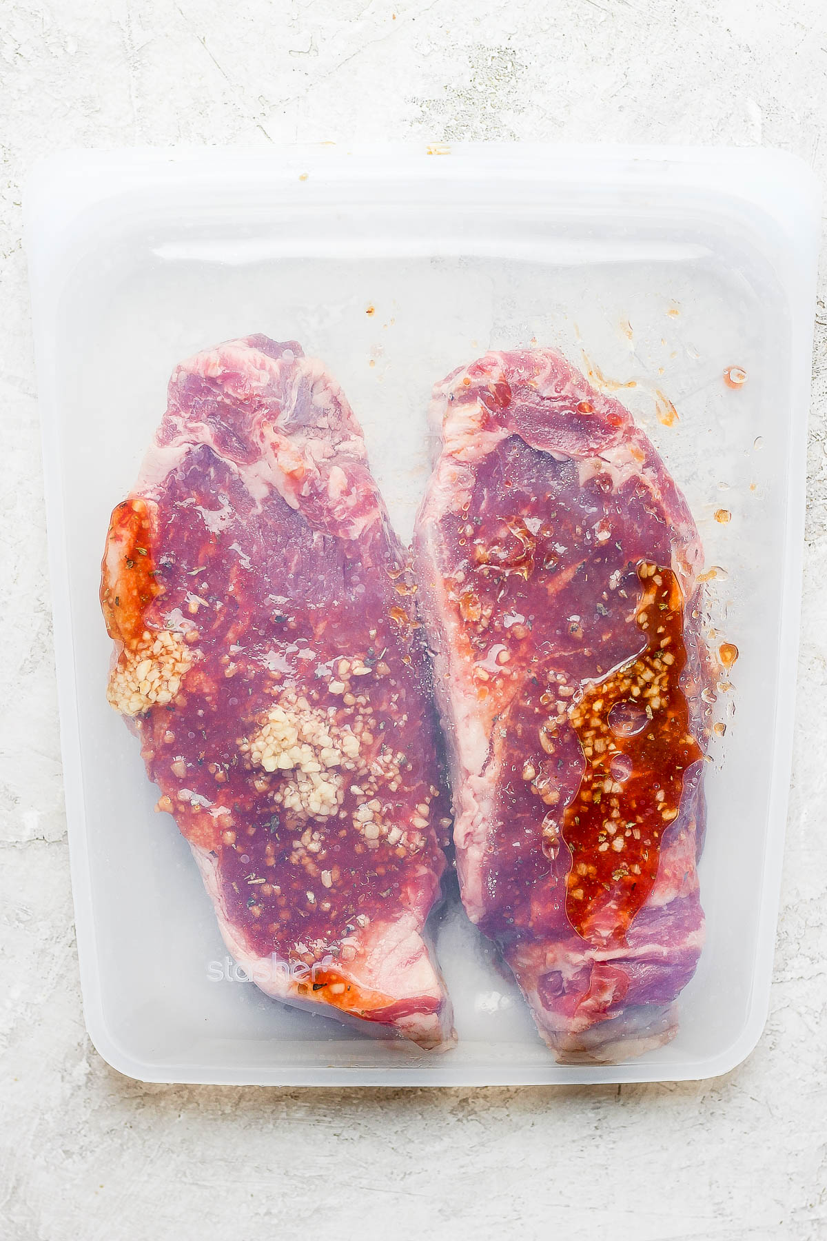 Two steaks in a stasher silicone bag with marinade inside. 