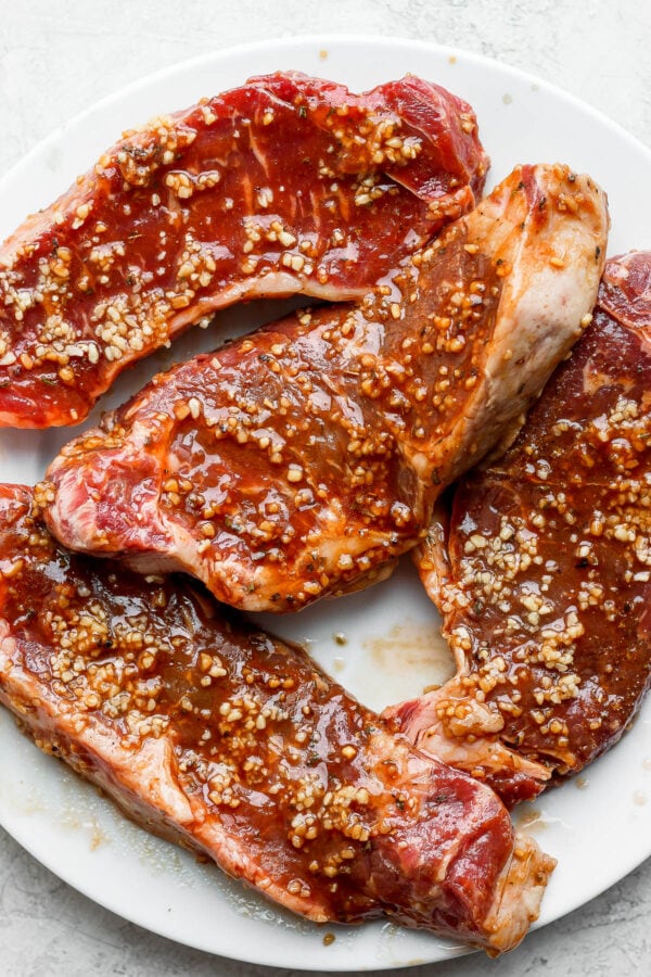 Four steaks covered in the best steak marinade.