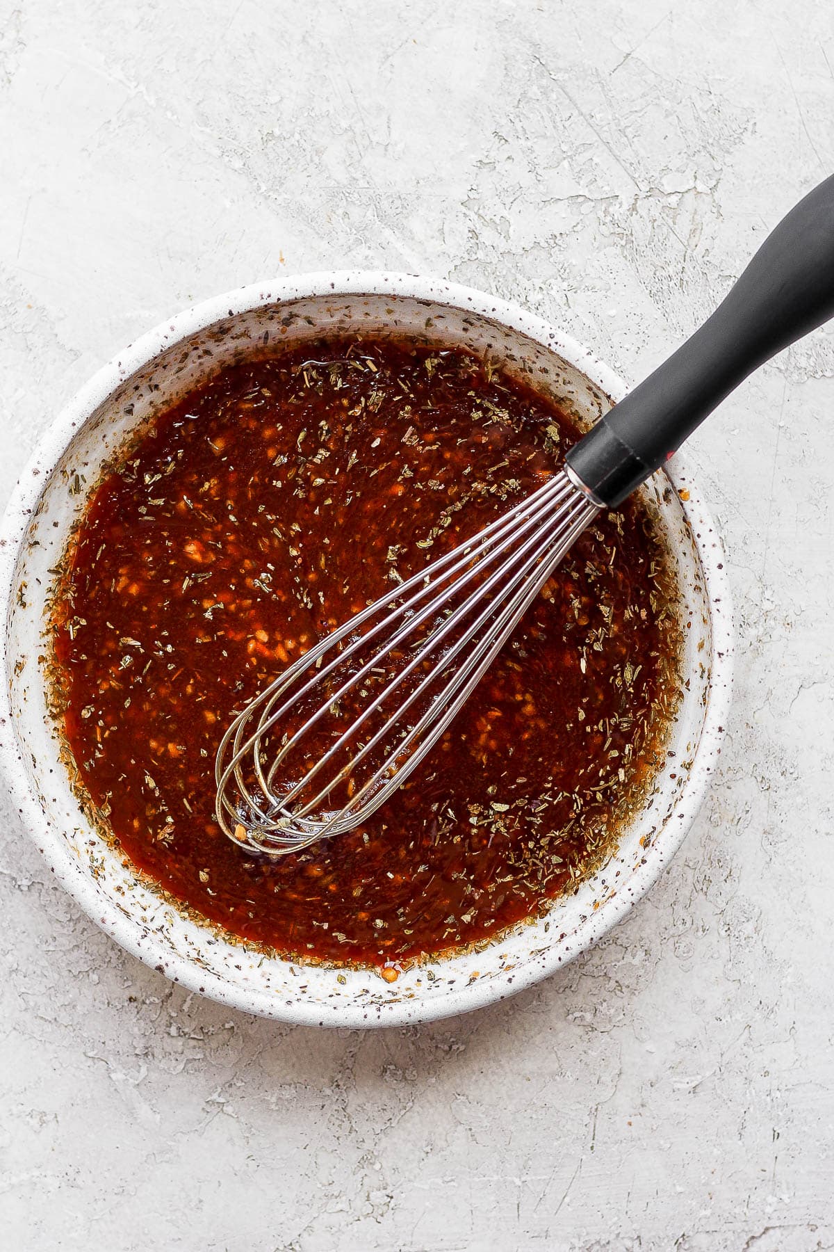 Steak marinade in a bowl with a whisk sticking out. 