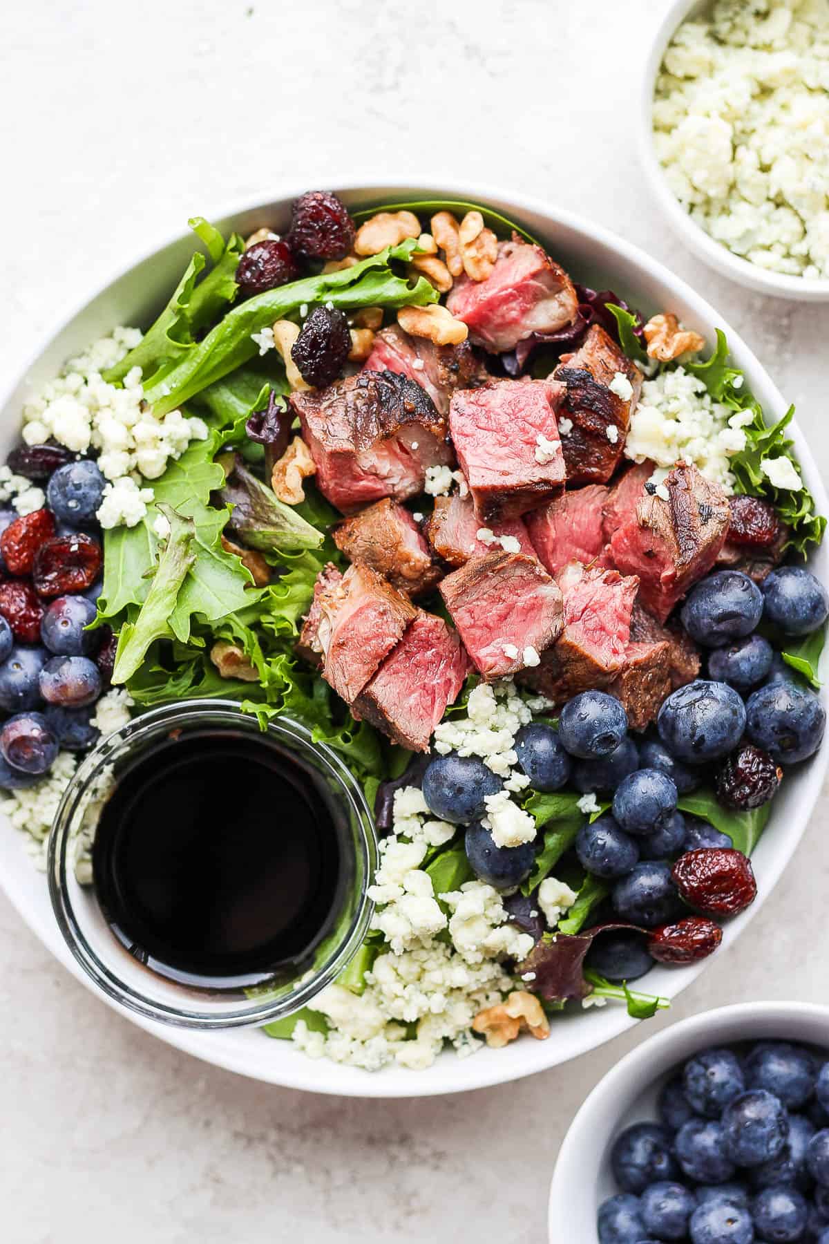 Easy steak salad in a bowl with a dish of dressing.