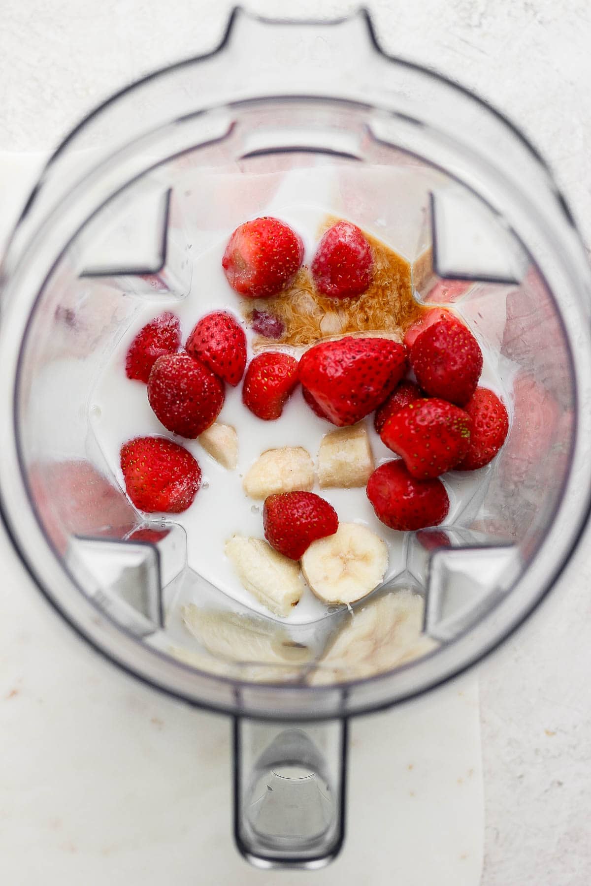 Strawberry banana smoothie ingredients in a blender.