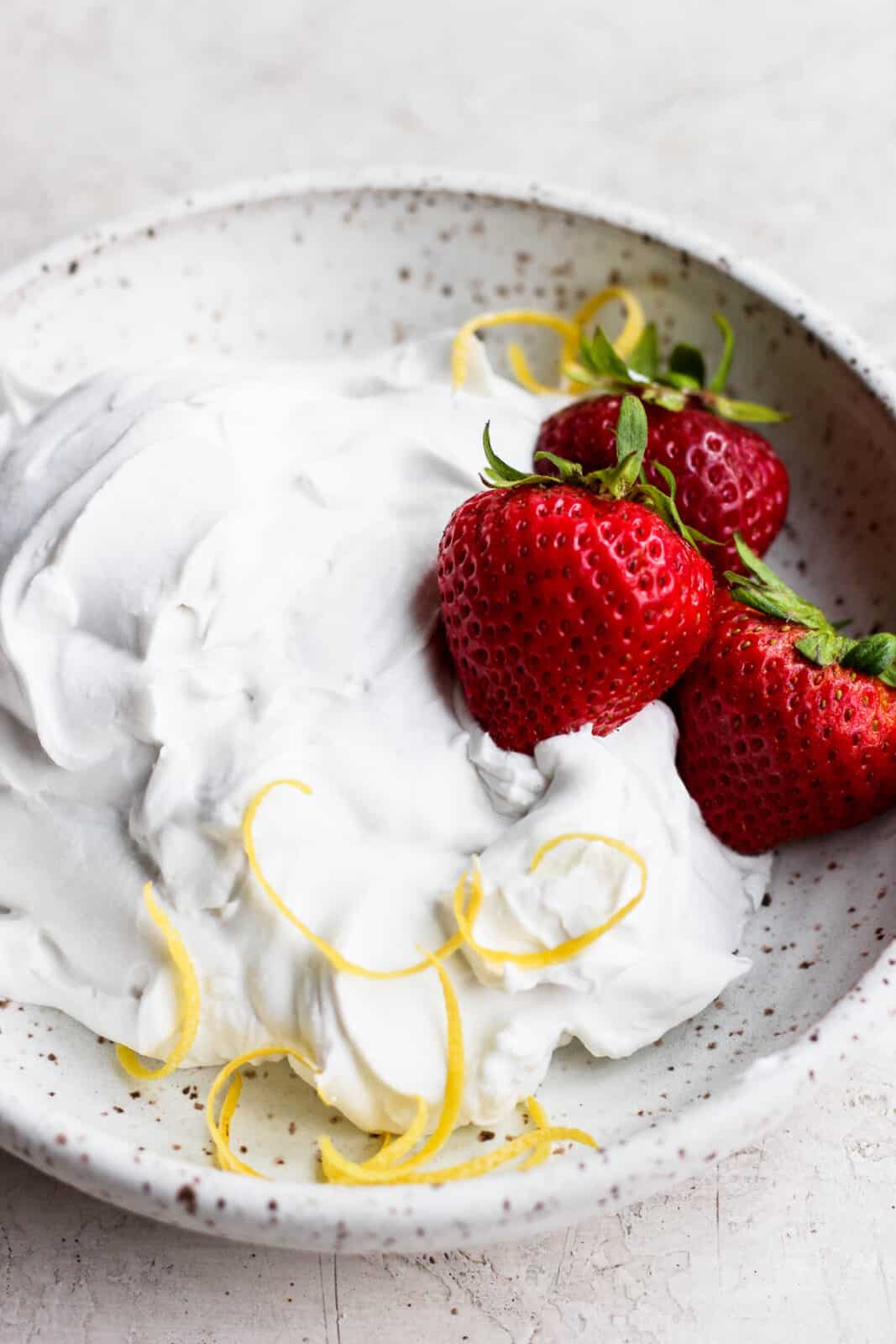 Dairy free whipped cream in a bowl with strawberries.